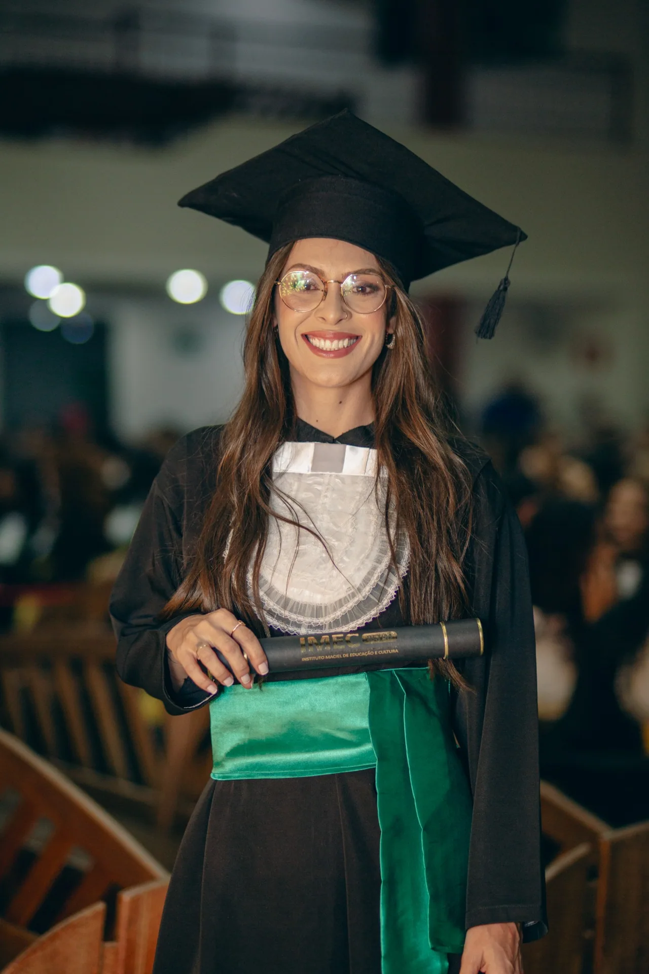 Formanda de óculos com diploma em cerimônia da WM Formaturas